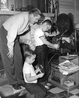 Dan, Richard (kneeling) and Peter Duryea Threading Their Home Projector (c. 1949)